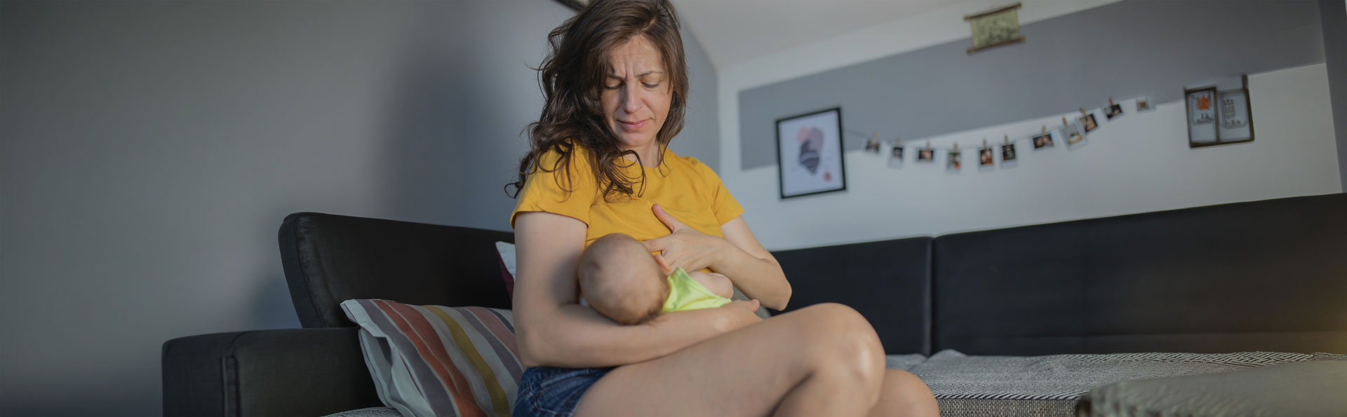 Woman breastfeeding baby on living room sofa