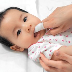 bac_Baby Baby lying down while adult gently cleans their teeth with a cloth.